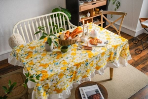 Detail shot of pastoral yellow floral tablecloth with elegant white ruffled edges