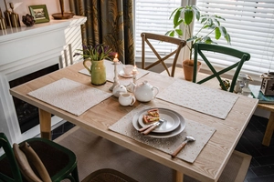 Close-up of four floral print fabric placemats on a wooden table in a cozy dining room
