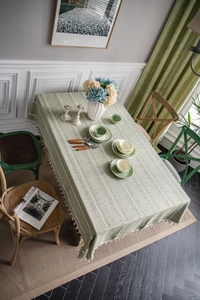 Detail of light green cotton linen tablecloth with white embroidery and tassel fringe edges