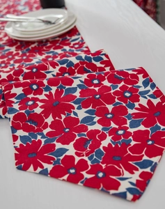 Detail of red and blue floral print table runner on textured cotton linen fabric
