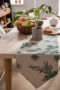 Detail of pine needle print table runner on light wood surface with rustic home decor