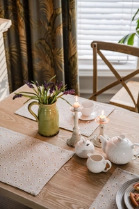 Close-up of cream table runner with yellow daisy print on rustic wooden surface