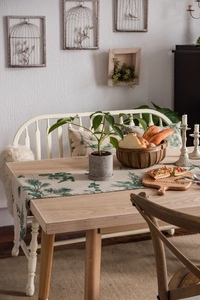 Close-up of linen table runner with green pine needle print on wooden dining table