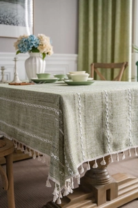 Detail of green cotton linen tablecloth with white embroidery and fringed edges