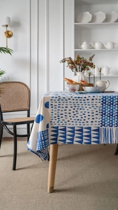 Detail of blue geometric patterns on cotton linen tablecloth draped over a dining table