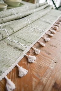 Detail showing green table runner with white wave weave, hollow crafts and cotton tassels