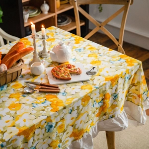 Yellow floral tablecloth with white ruffled edges in a warm pastoral dining setting