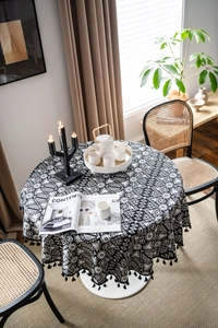 Detailed view of heavy fabric round tablecloth with geometric patterns and black tassels