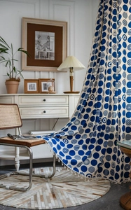 Detail view of blue polka dot patterned cotton linen curtain fabric with white tassel trim