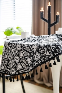 Close-up of thick geometric woven tablecloth with black tassels and boho pattern