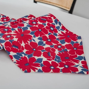Red and blue floral table runner with pointed edges on white tabletop setting