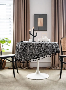 Close-up of black and white geometric round tablecloth with elegant black tassel trim detail