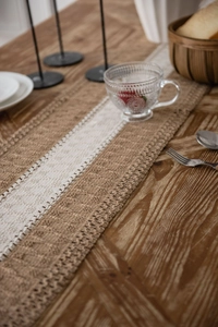 Close-up of rustic jute table runner with delicate white lace center and woven texture