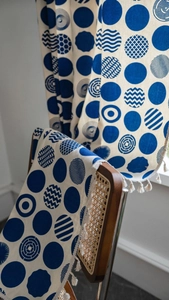 Detail of blue geometric dot print curtain fabric with elegant white tassel fringe