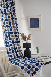 Detail view of blue geometric dot pattern curtains with beige tassels and cotton-linen texture