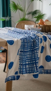 Close-up of geometric blue printed cotton linen tablecloth on a wooden table in a cozy room