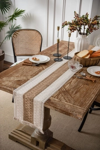 Detail of bohemian cotton linen table runner with woven fringe on a rustic wooden table