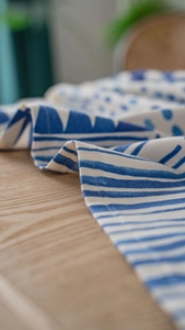 Detail of blue and white geometric linen tablecloth with stitching on wooden desk