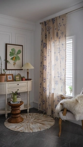 Detail of blue floral print linen curtain with decorative side tassel ball fringe