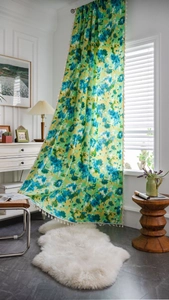 Détail d'un rideau bohème avec imprimé tie-dye vert et bordure décorative à pompons blancs