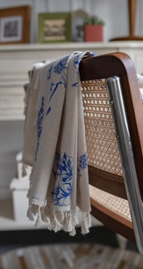 Close-up of beige cotton linen fabric with blue floral print and fringe details
