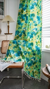 Vue détaillée du rideau tie-dye vert avec des glands à pompons blancs et tissu en coton-lin