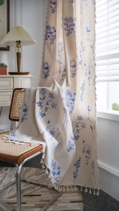 Detail of blue floral print curtain with fringe edges on cream cotton linen fabric