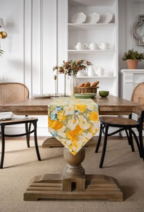 Detailed view of yellow floral pattern on fabric table runner over a dark wood table