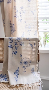 Detailed view of floral cotton linen curtain fabric featuring blue flowers and fringe