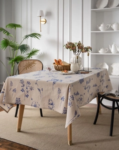 Close-up of rectangular linen tablecloth featuring blue floral patterns on a wooden table