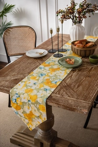 Detailed close-up of pastoral floral table runner with yellow flowers on rustic wood table