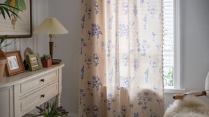 Detail of floral print curtains with blue blossoms and decorative beige tassel fringe