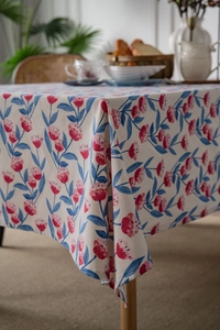 Detail of pink floral cotton linen tablecloth with soft corner drape in warm dining setting