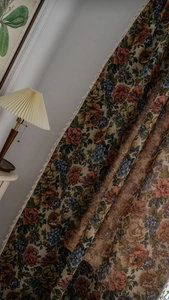 Detail eines Vintage-Jacquard-Vorhangs mit Rosenmuster und cremefarbenen Quastenkanten