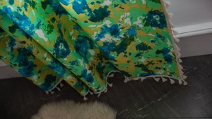 Détail du tissu tie-dye vert et bleu avec glands en coton blanc pour rideaux bohèmes