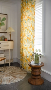 Detailed close-up of floral print curtain with orange flowers and white fringe trim
