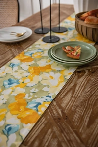 Detailed texture of yellow floral table runner on dark wood with dining accessories