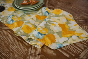 Detailed macro view of yellow floral table runner with textured linen fabric on wood