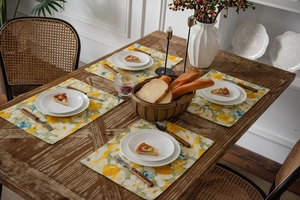 Close-up of four-piece cotton linen placemat set with yellow floral pattern for dining table