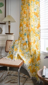 Detail of floral yellow curtain with white cotton tassels and textured linen fabric