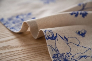 Detailed close-up of blue floral print on beige linen fabric with natural weave texture