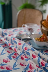 Detail of pink tulip floral pattern on a beige linen tablecloth in a cozy home setting