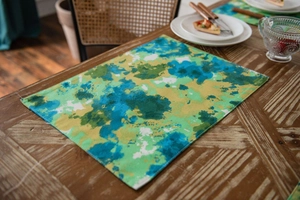 Detail of green tie-dye placemat with watercolor pattern on dark wooden table