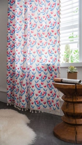 Detail eines Vorhangs im Boho-Stil mit roten Blumen, blauen Blättern und weißen Quasten