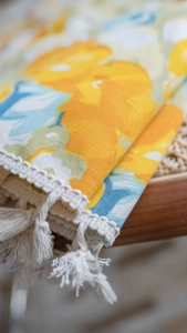 Detailed view of yellow floral pattern curtains with white lace edges and fringe tassels