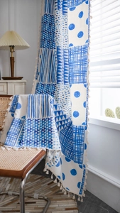 Detail eines blauen Boho-Vorhangs mit geometrischem Muster und weißen Quasten am Saum