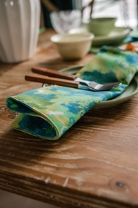 Detail of green tie-dye cotton linen placemat with premium stitching on wooden table