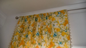 Close-up of yellow floral curtain fabric featuring delicate beige tassel edge detailing