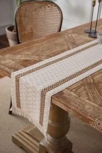 Close-up of cotton linen woven table runner with tassels on a vintage wooden dining table