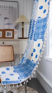 Detail von blau-weißem Vorhang mit geometrischem Muster und weißen Pompons am Saum